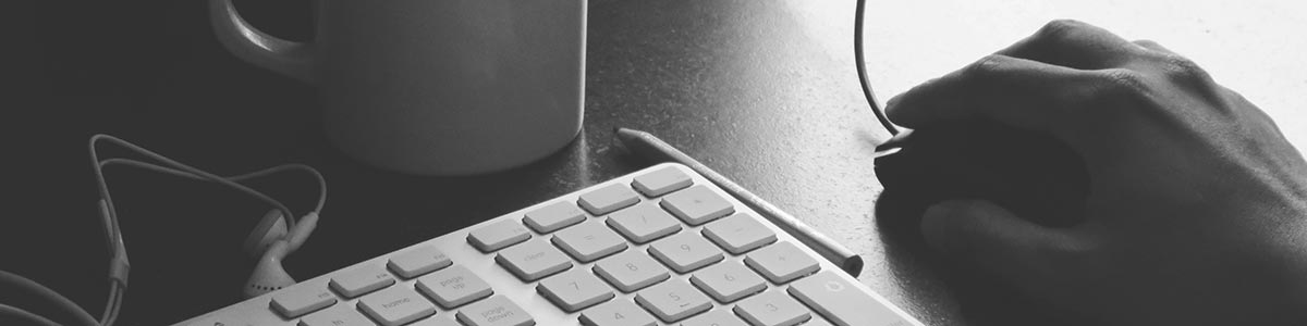 image of hands on a computer mouse next to a keyboard.